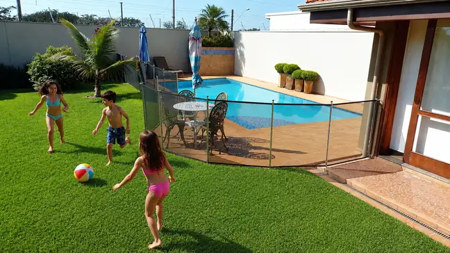 Crianças brincando perto de piscina com cerca de proteção